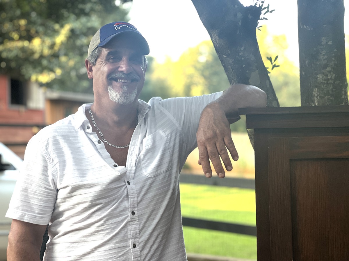 Brad outside, leaning on a post